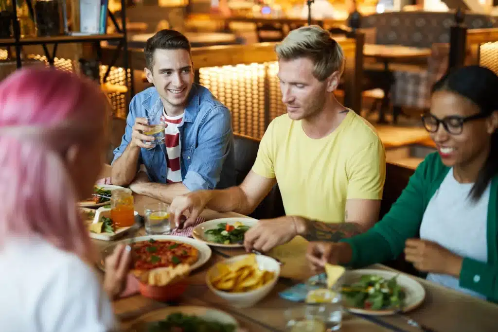 Friends and colleagues, shown are two men and two women at a restaurant enjoying a lunch planned from the Lunch Buddy Network