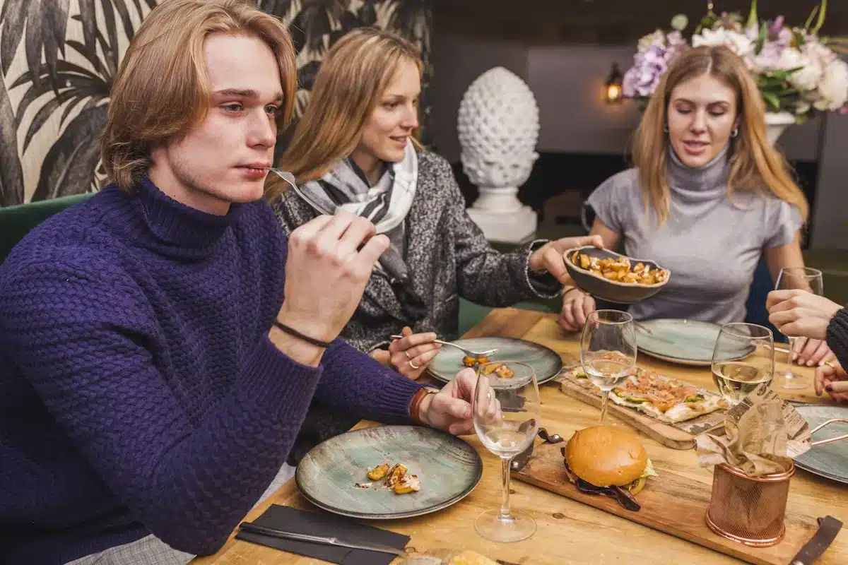 a group of four Some Gen Z friends having lunch together one is off camera