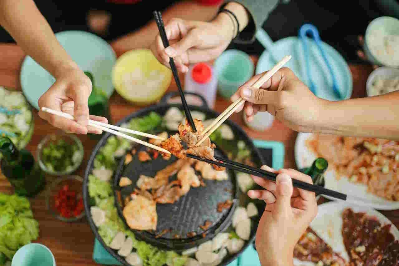 Best Lunch Places for Office Team Bonding Top View of People Holding Chopsticks with Beef Together at Korean barbecue