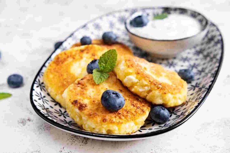 Cottage cheese pancakes with sour cream and blueberries on a light background. Breakfast or lunch
