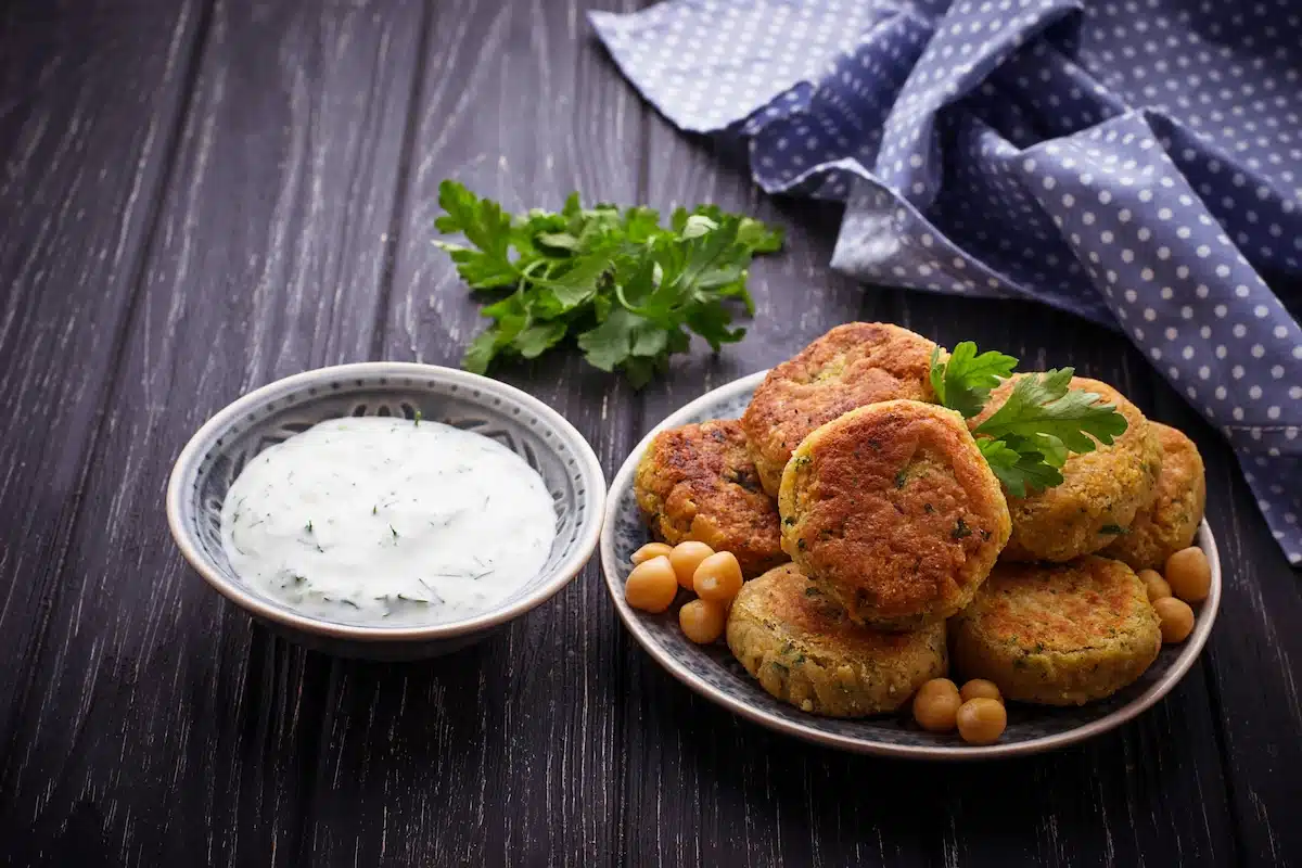 A bowl of tzatziki sauce beside a bowl with falfel balls