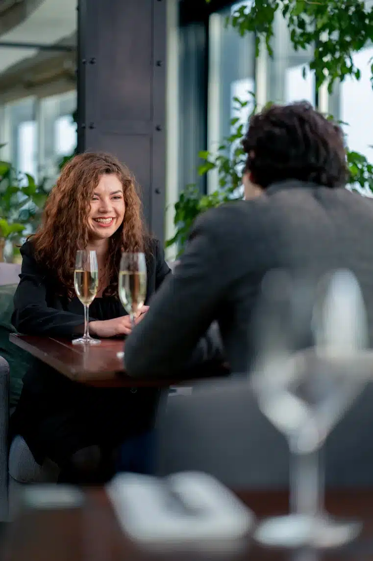 A man and a woman enjoying a first-date in a restaurant with glasses of wine