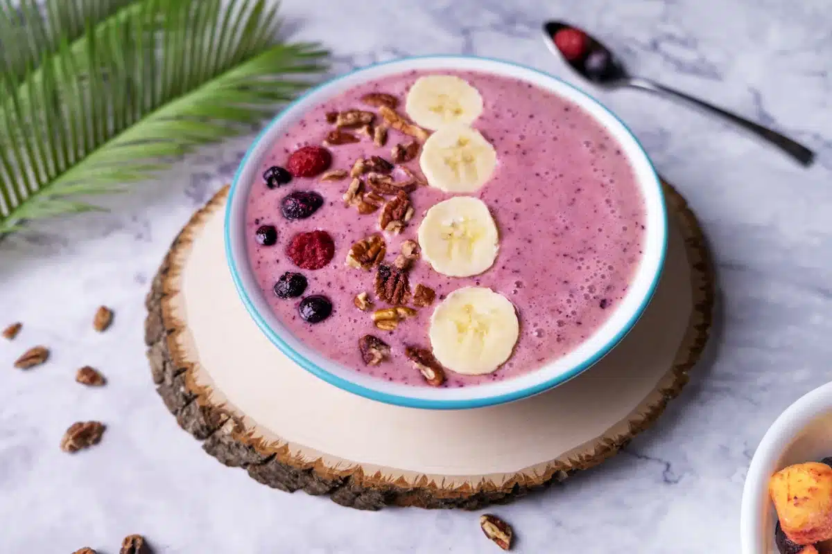 Fruit smoothie bowl topped with blueberries, raspberries, pecans and bananas.