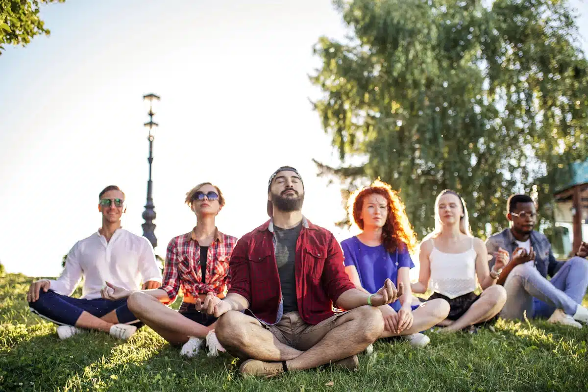 A group of six colleagues performing meditation on the grass