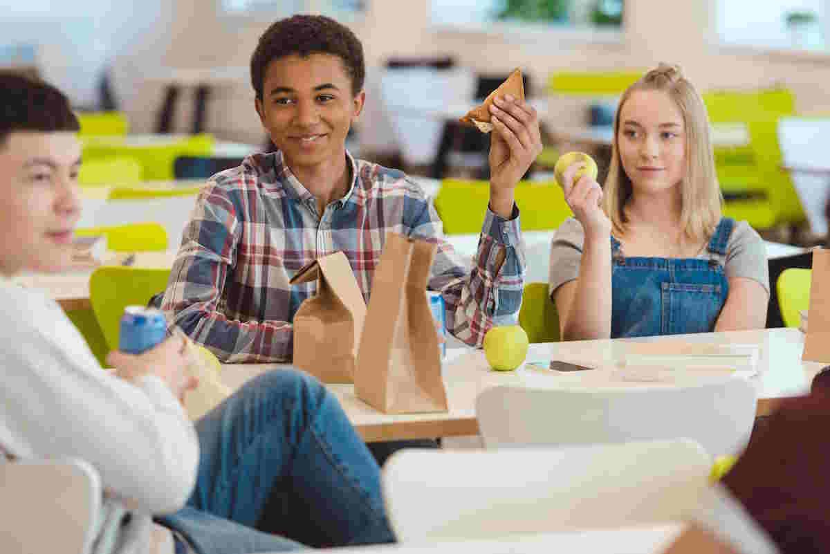 Healthy Lunches for Teenagers multiethnic group of high school students chatting while taking lunch at school cafeteria