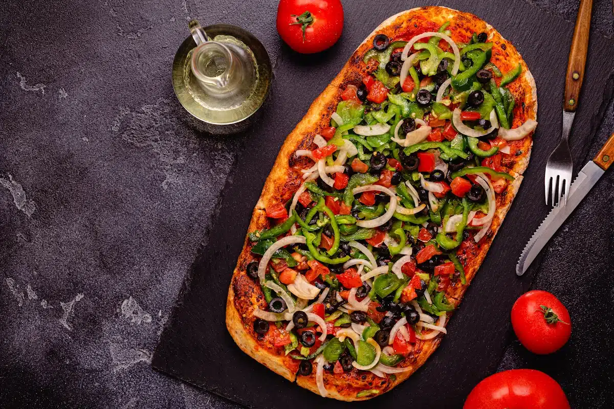 Homemade vegan pizza with tomatoes, peppers, olives, onions and herbs