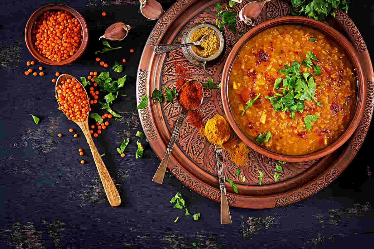 Indian Lentil Stew (Dal) | Vegan & Diabetic-Friendly. Indian Dhal spicy curry in bowl, spices, herbs, rustic black wooden background. Top view. Authentic Indian dish. Overhead. Flat lay