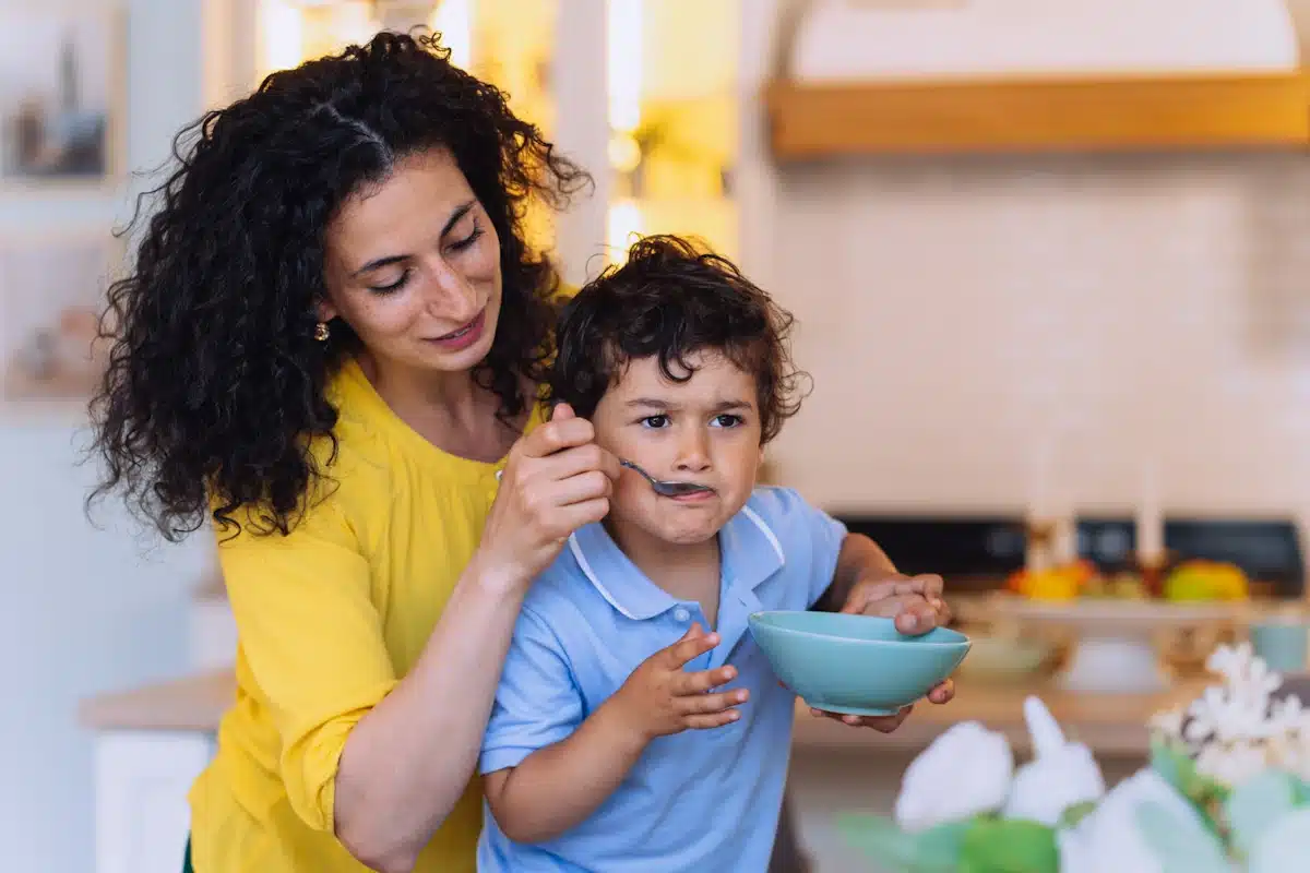 Introducing New Foods to Young Children woman feeding her rebellious son