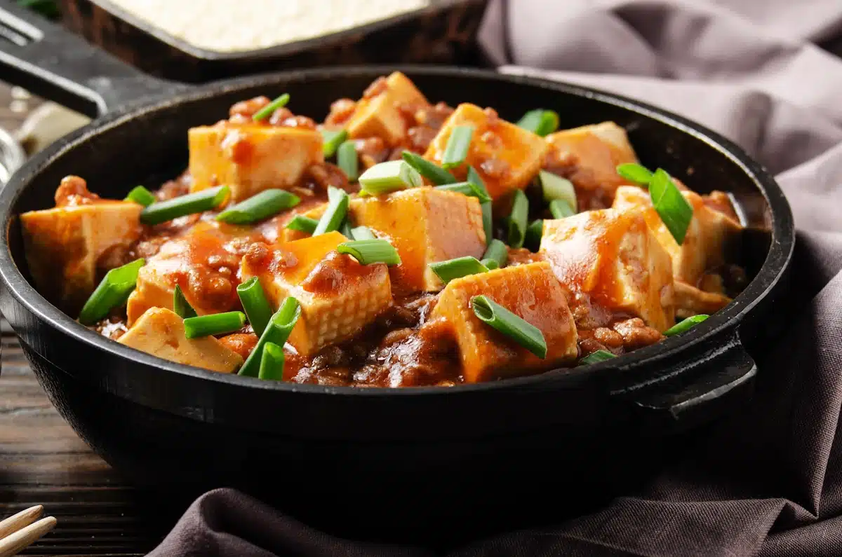 Mapo tofu in cast iron skillet with pork chopped chives soy sauce sichuan pepper garlic and spices