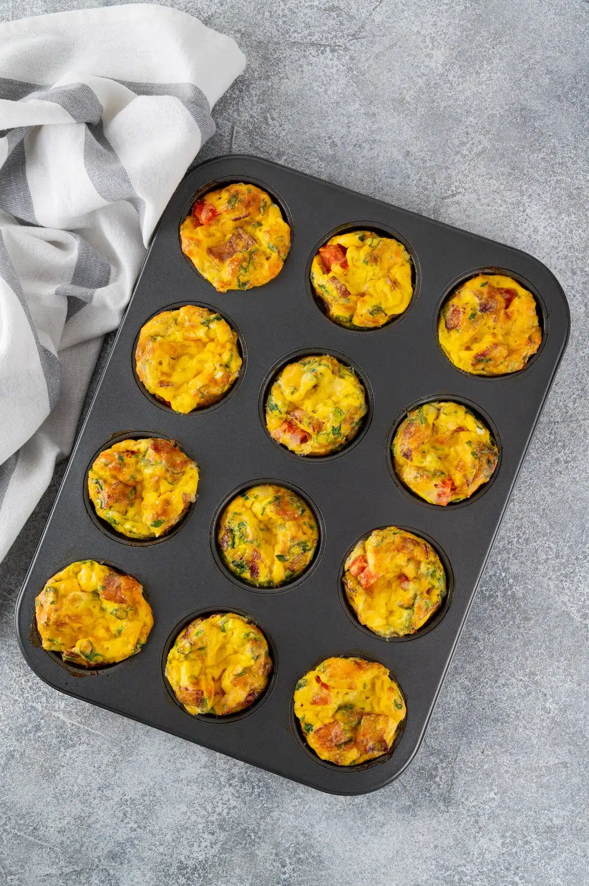 Egg muffins or egg bites with bacon, cheese, vegetables and herb in a baking form