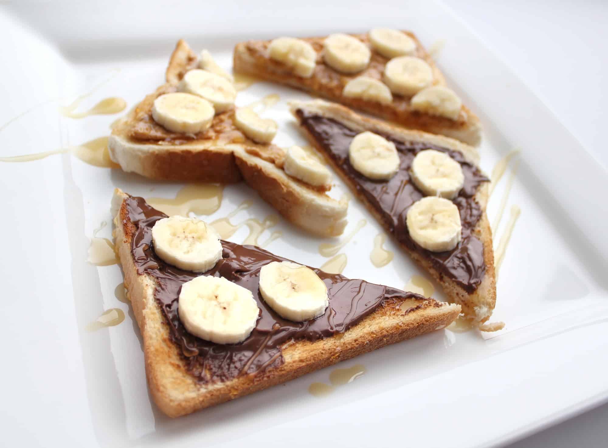 Breakfast food, triangles of toast with peanut butter, banana and Nutella drizzled with maple syrup