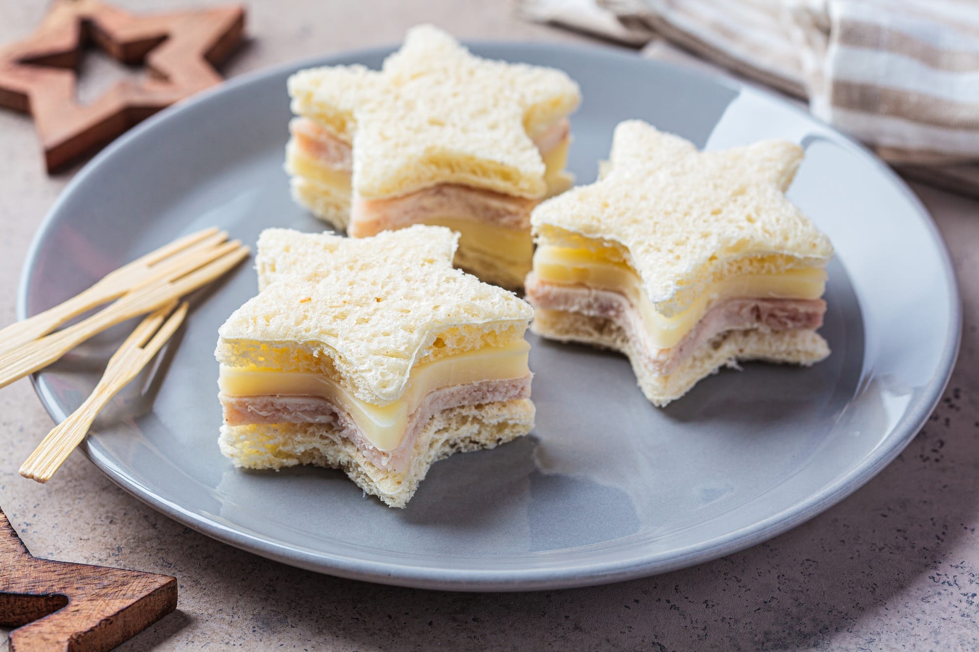 Christmas food - Star-shaped cheese and ham sandwiches on gray plate. Festive food concept.