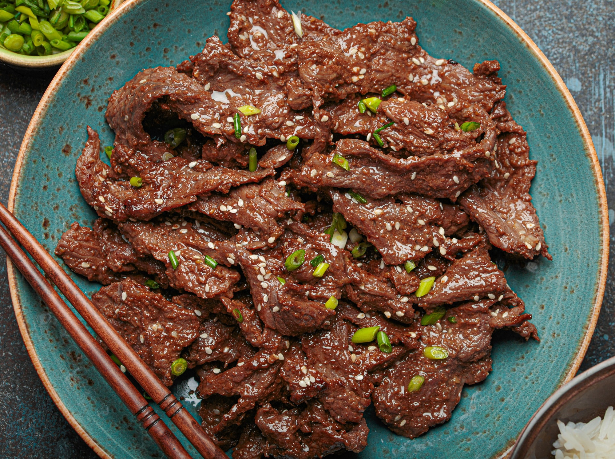 Close up of delicious bulgogi dish served with rice and green onions top view, Korean cuisine