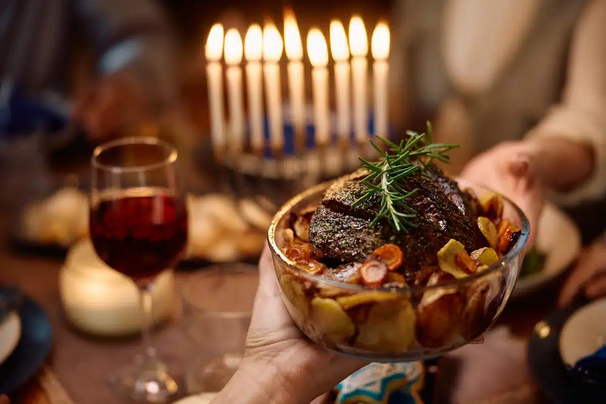 Close up of Jewish people having beef brisket during Hanukkah meal at dining table