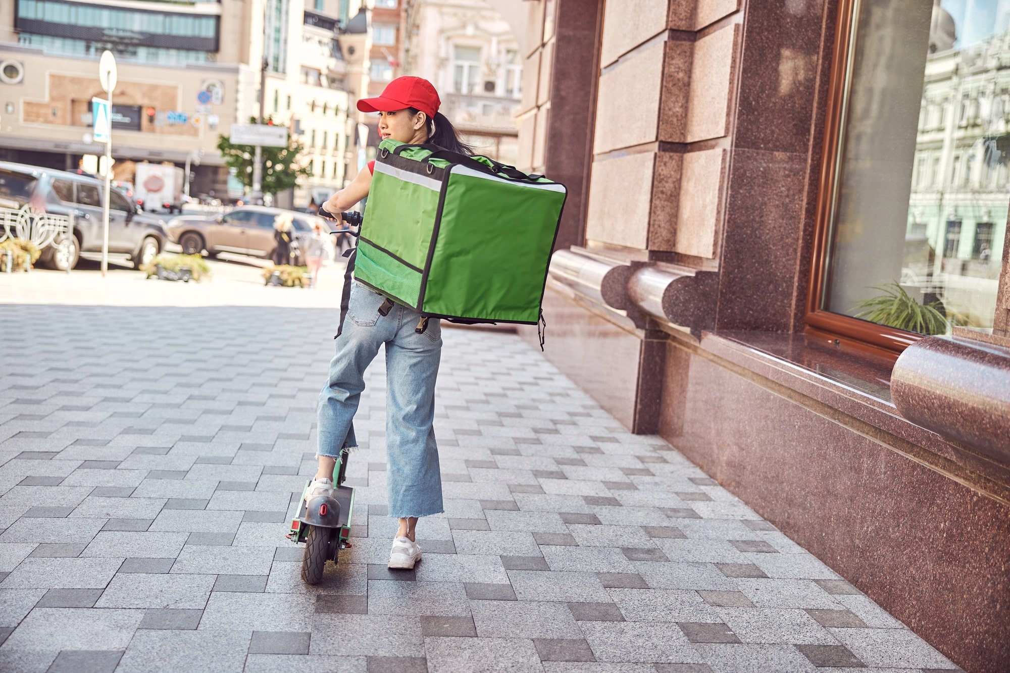 food Delivery service woman riding scooter in big modern city