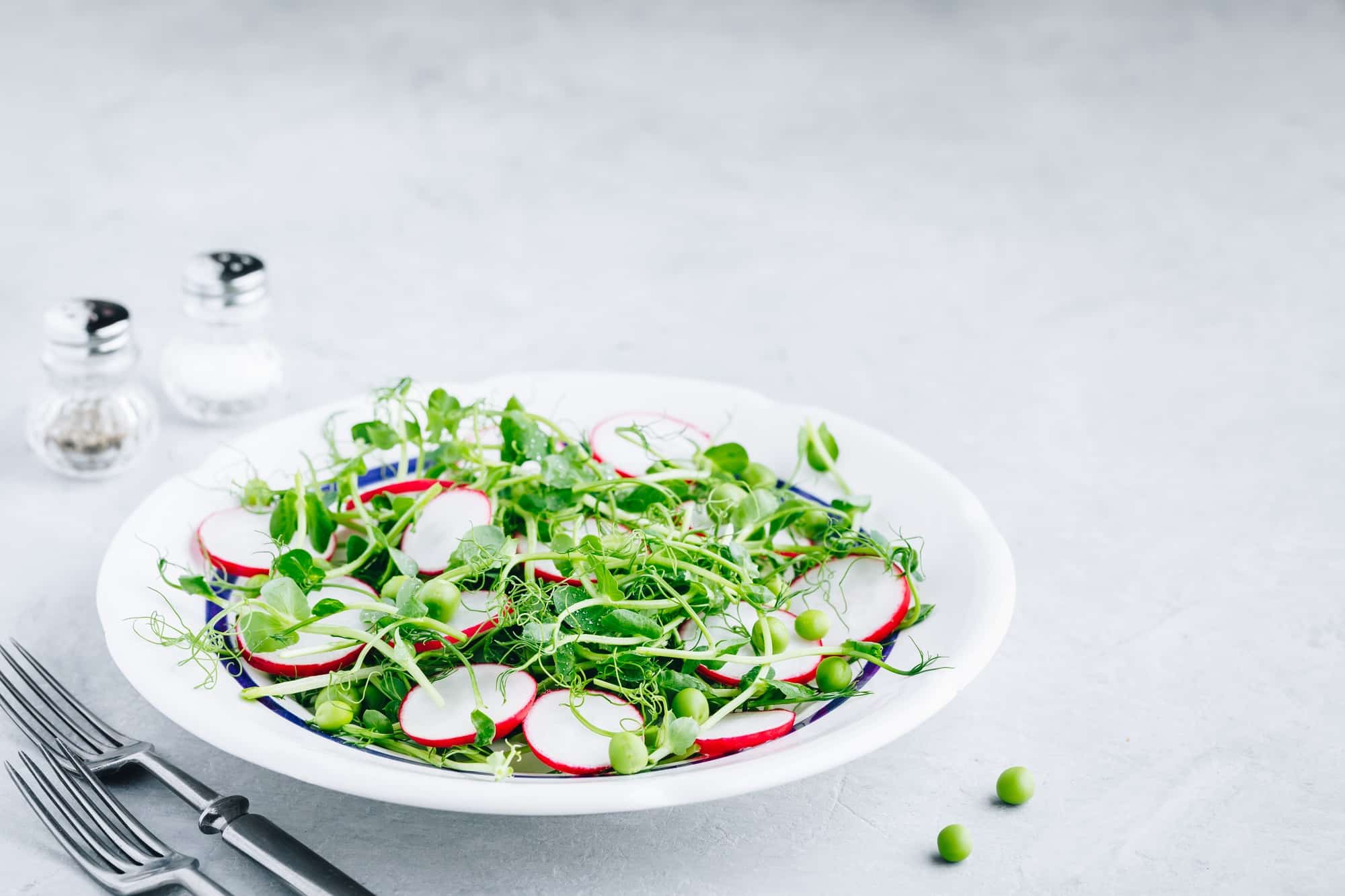 Fresh green pea shoots salad with radishes.