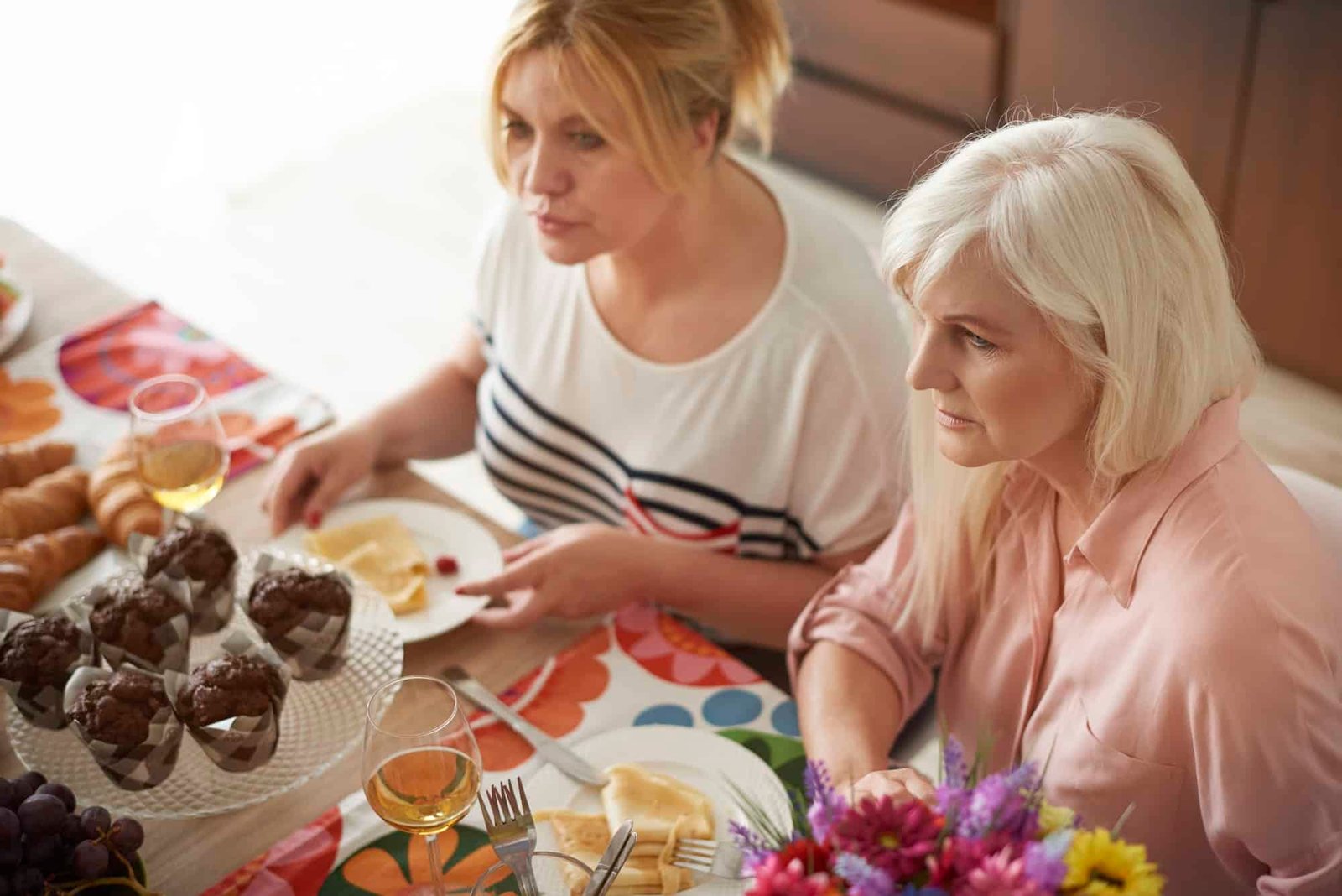 Two women gossiping over lunch with friends