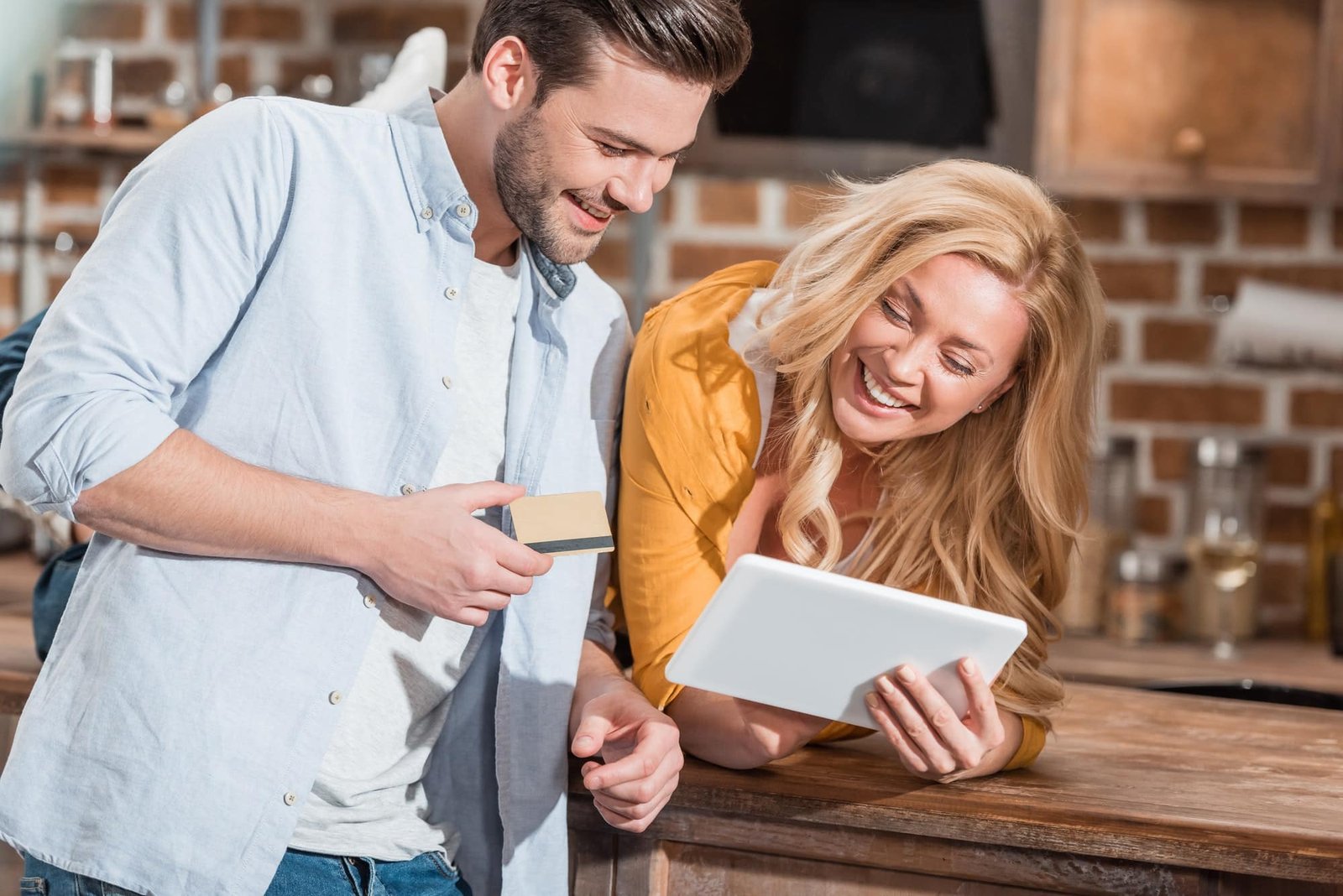 happy beautiful couple shopping at the Lunch Pro Shop making e-shopping with tablet on table at kitchen