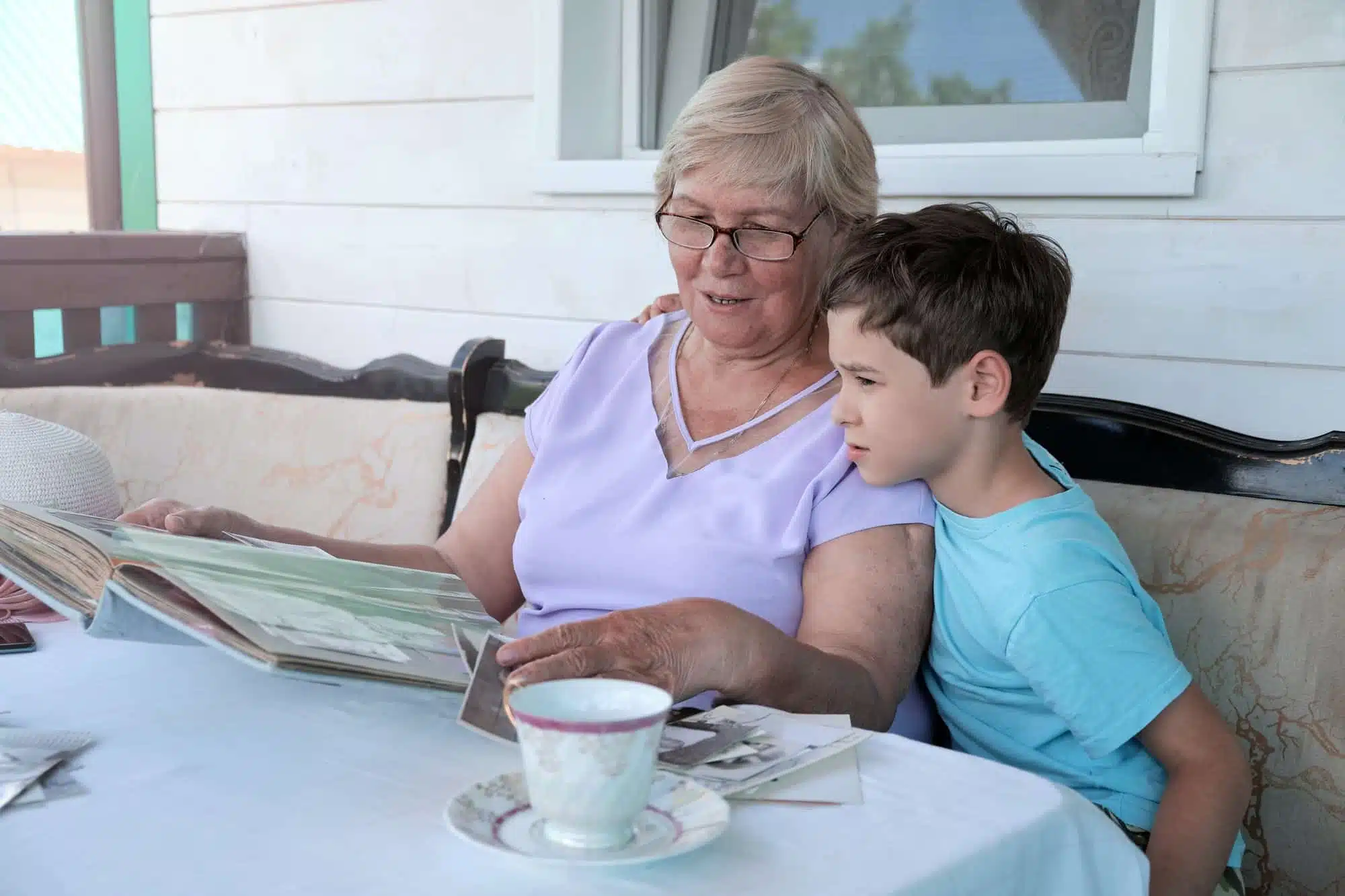 Grandmother and grandson are looking at an photograph album in this lunch with relatives