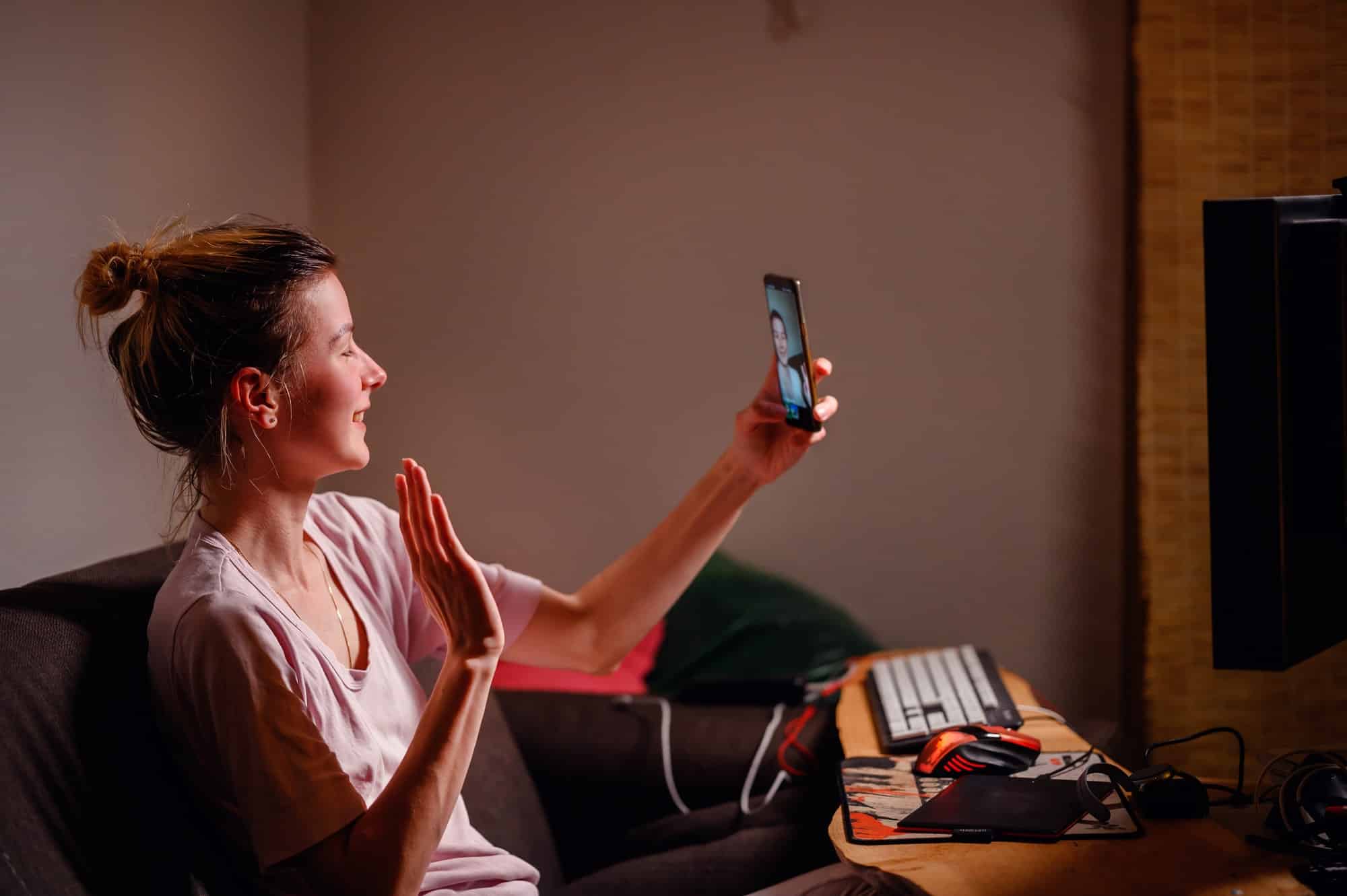 Happy young woman in t-shirt speaking via smartphone and Facetime at evening