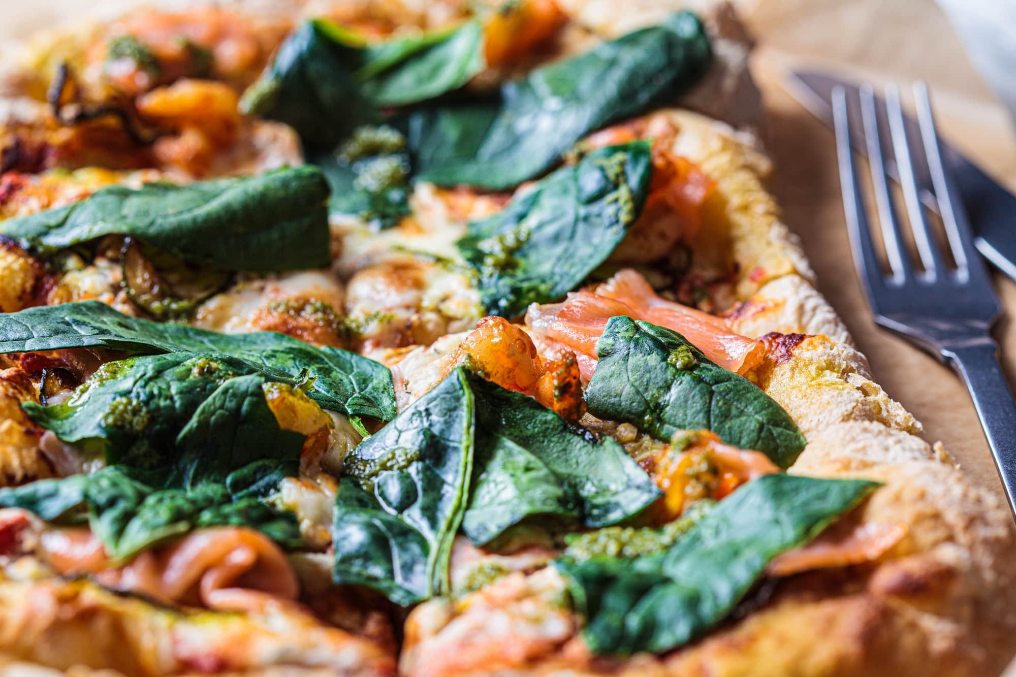 Homemade pizza with salmon, pesto and shrimps. Comfort food theme.