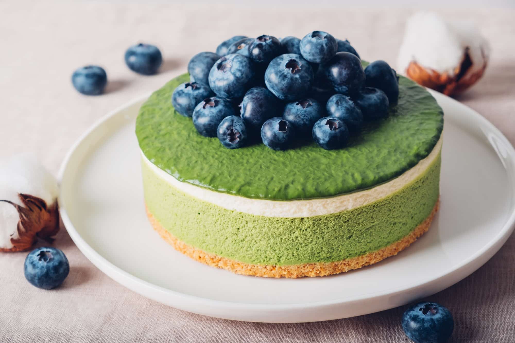 Layered matcha cheesecake on white plate.