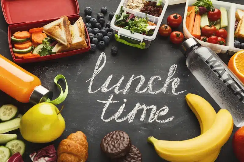 Lunch boxes filled with healthy food on black board