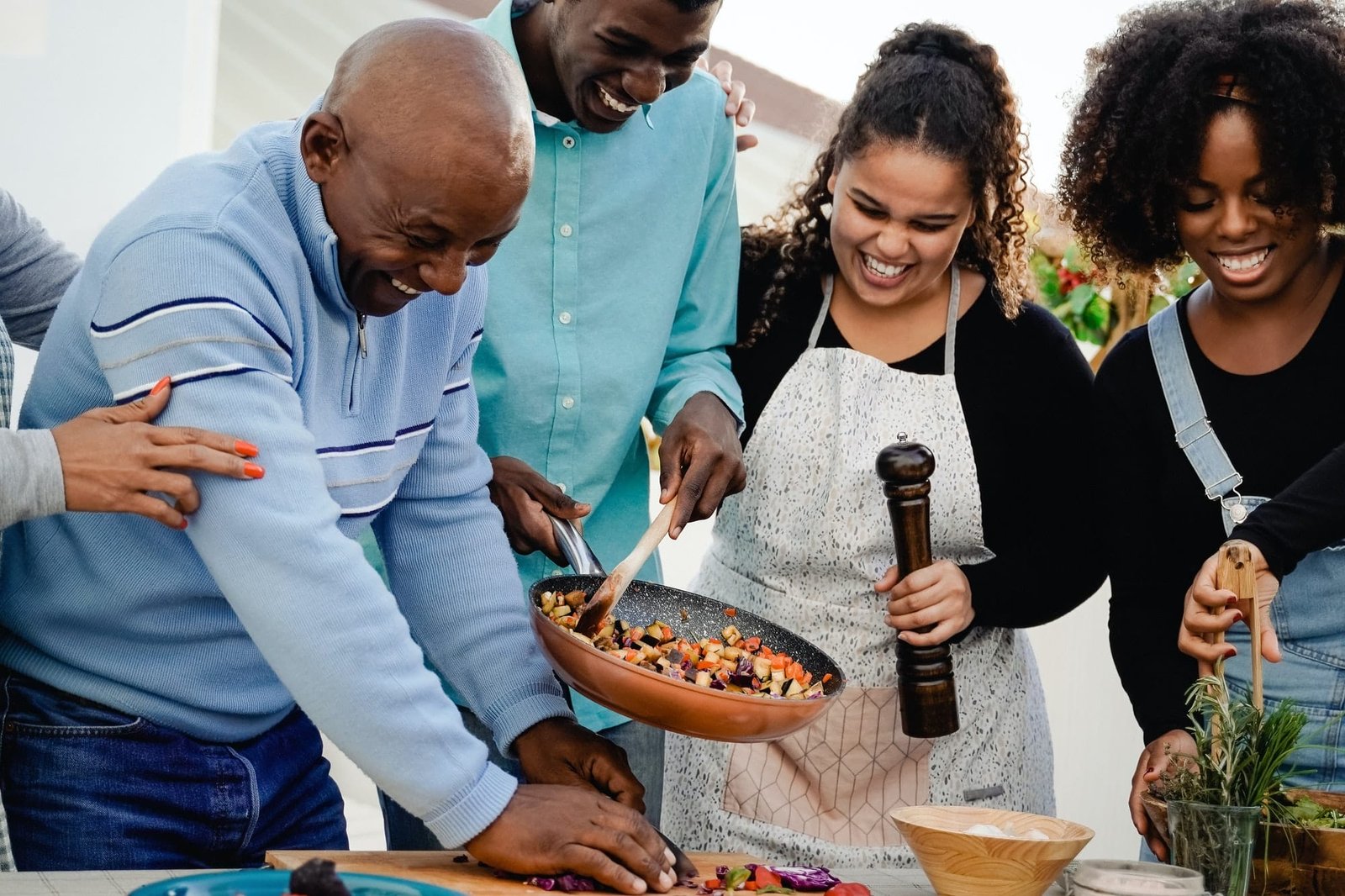 Outdoor kitchen: Happy African family cooking together at home patio