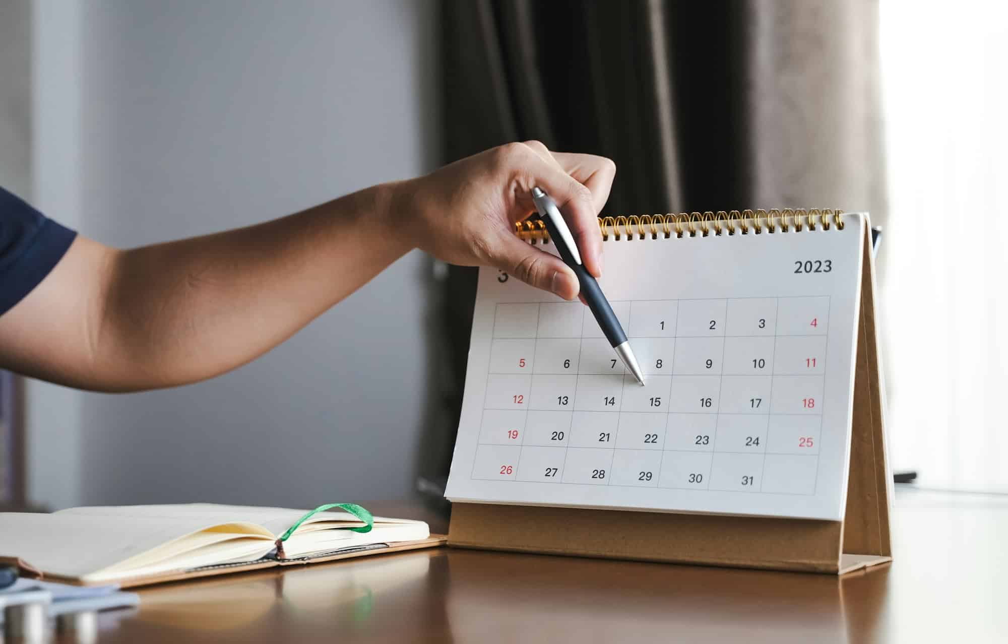 Effective planning and preparation for lunch with clients is crucial to making a positive impression seen here is a man at his desk pointing at a date on his desk calendar with his pen