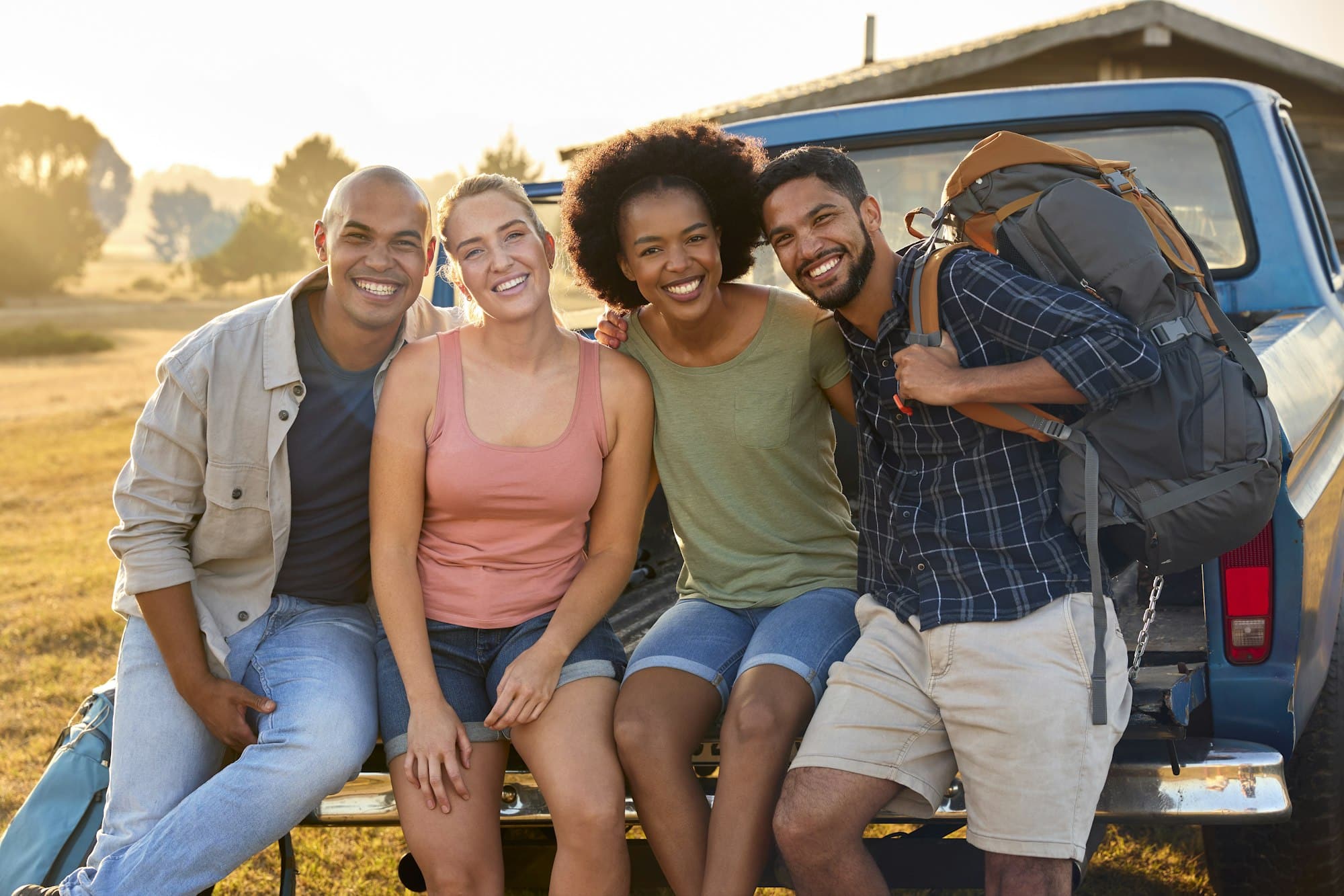 Friends Sitting On Tailgate Of Pick Up Truck On The Way to an Outdoor Concert