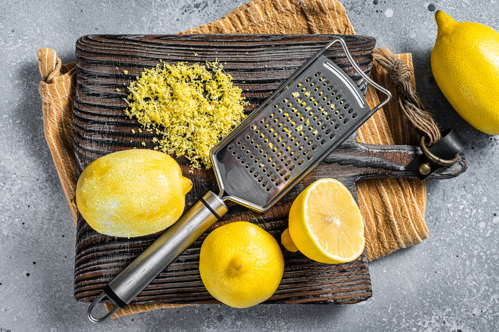 Raw grated Lemon Zest peel on wooden board. Gray background. Top view