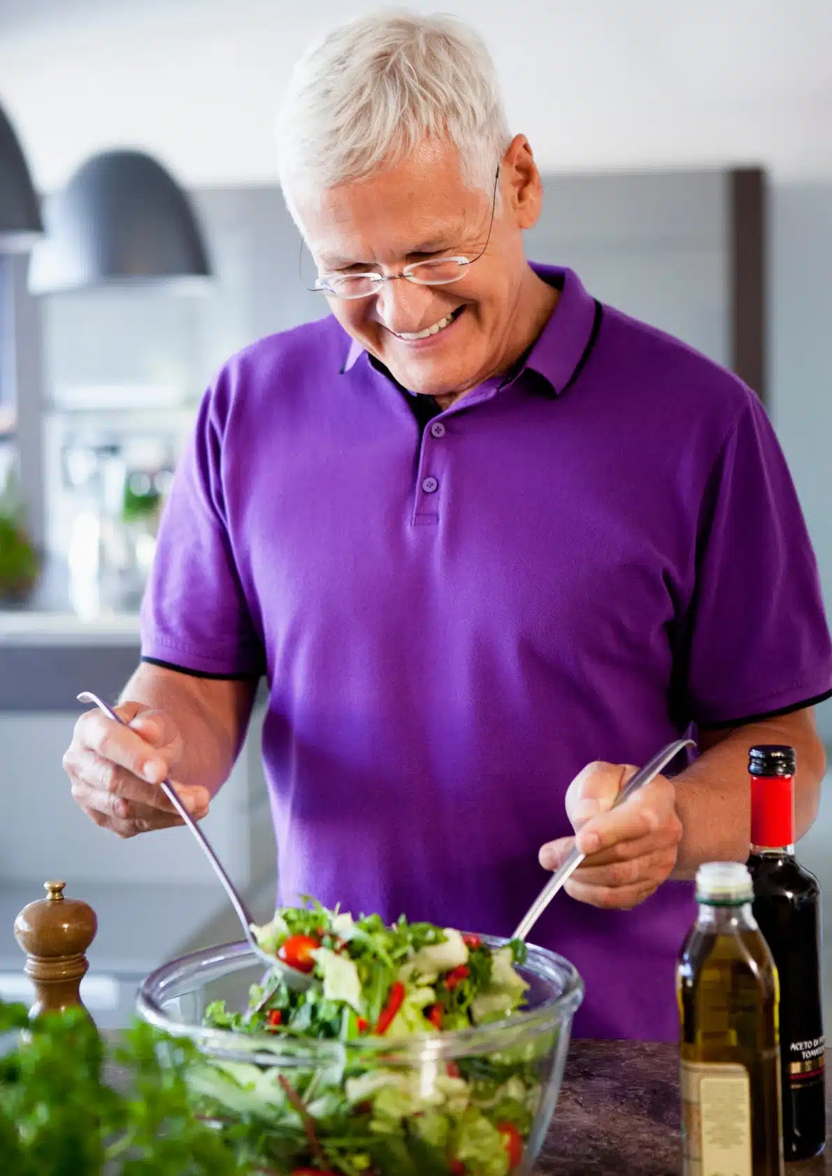 Photo of an older gentleman preparing a salad for lunch