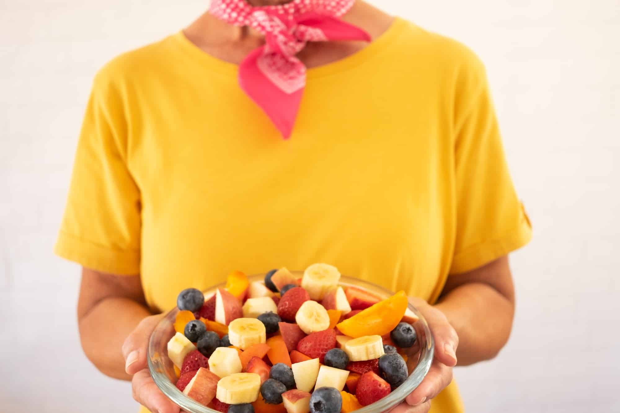 Senior woman holding bowl of fresh seasonal fruit ready to eat. Breakfast or lunch, eat healthy