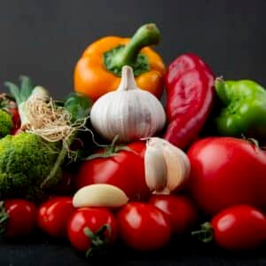 side view of vegetables as broccoli, tomato, garlic and others on gray background