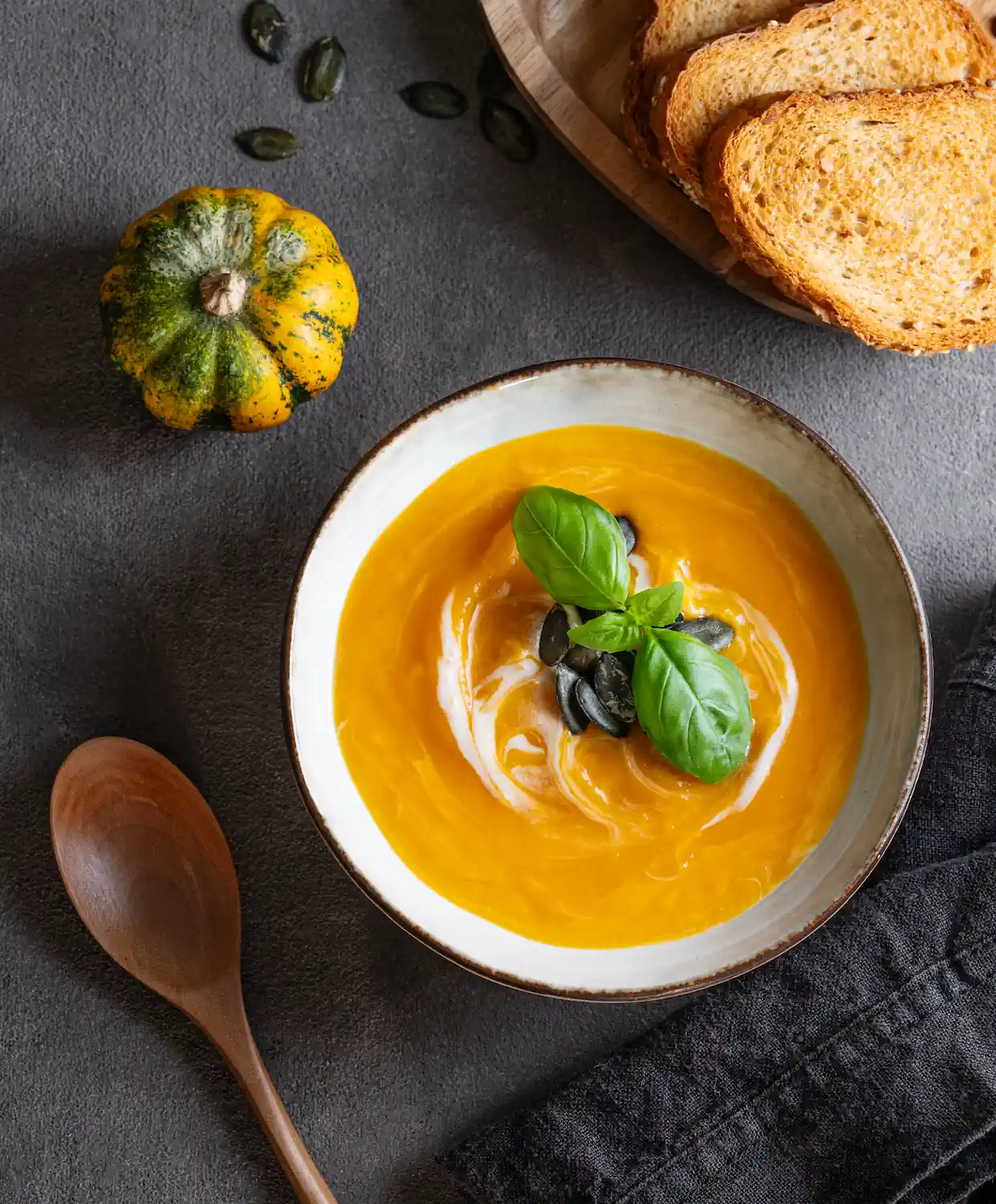Bol de soupe de potimarron onctueuse parsemée de graines de courge, avec du pain grillé