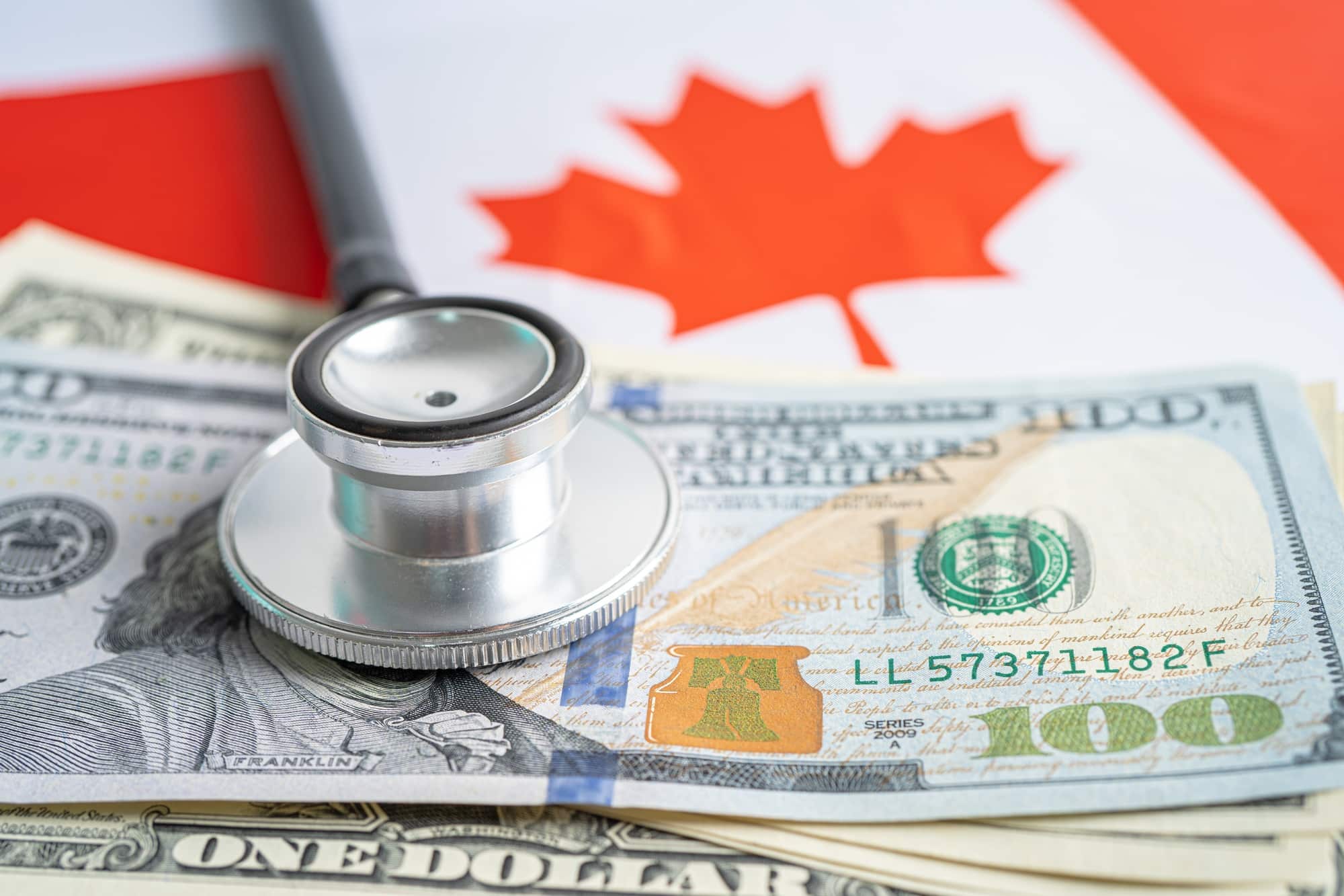 Stethoscope with US dollar banknote money on Canada flag.