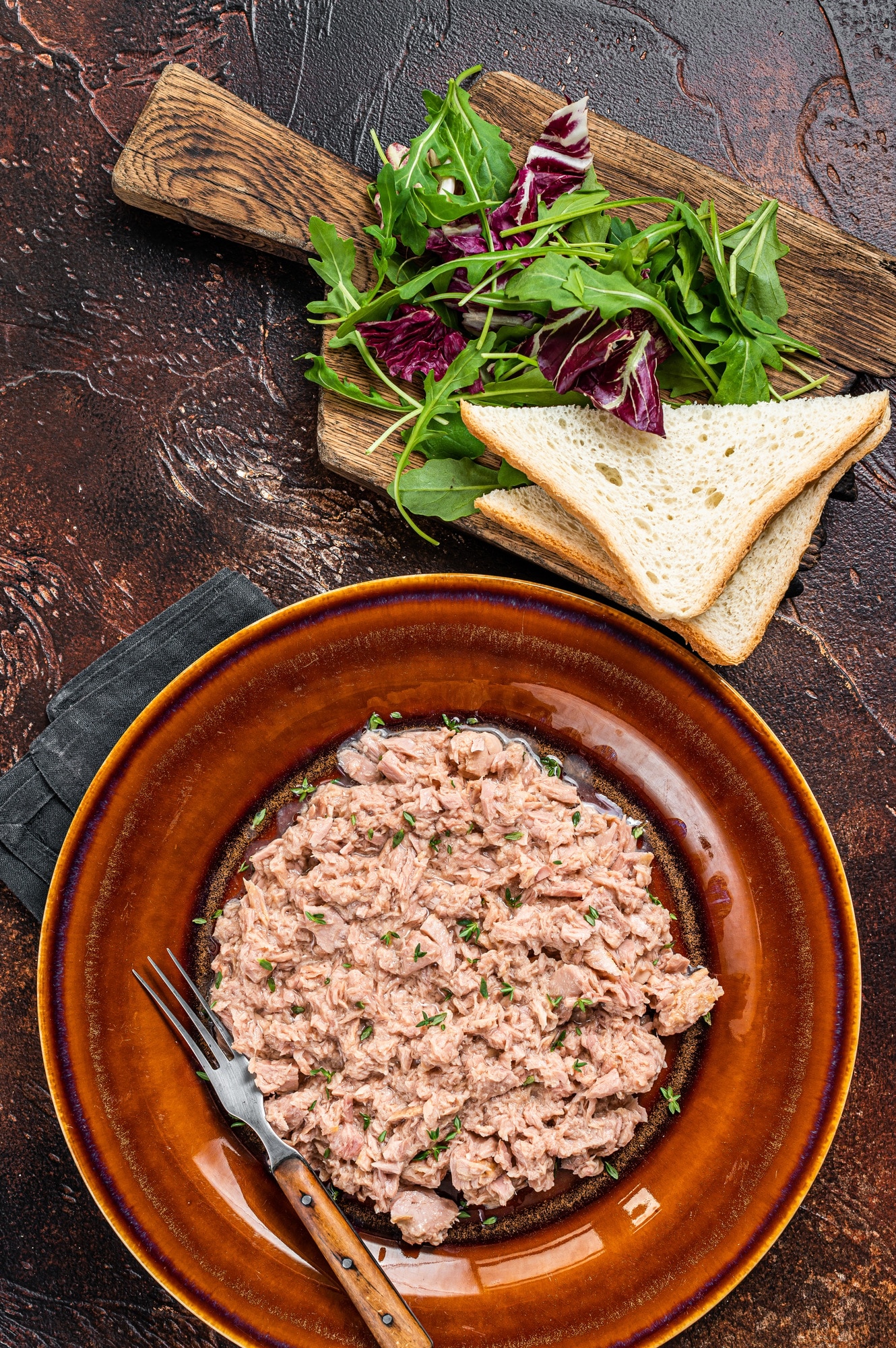 Tuna canned fish with bread and salad. Dark background. top view