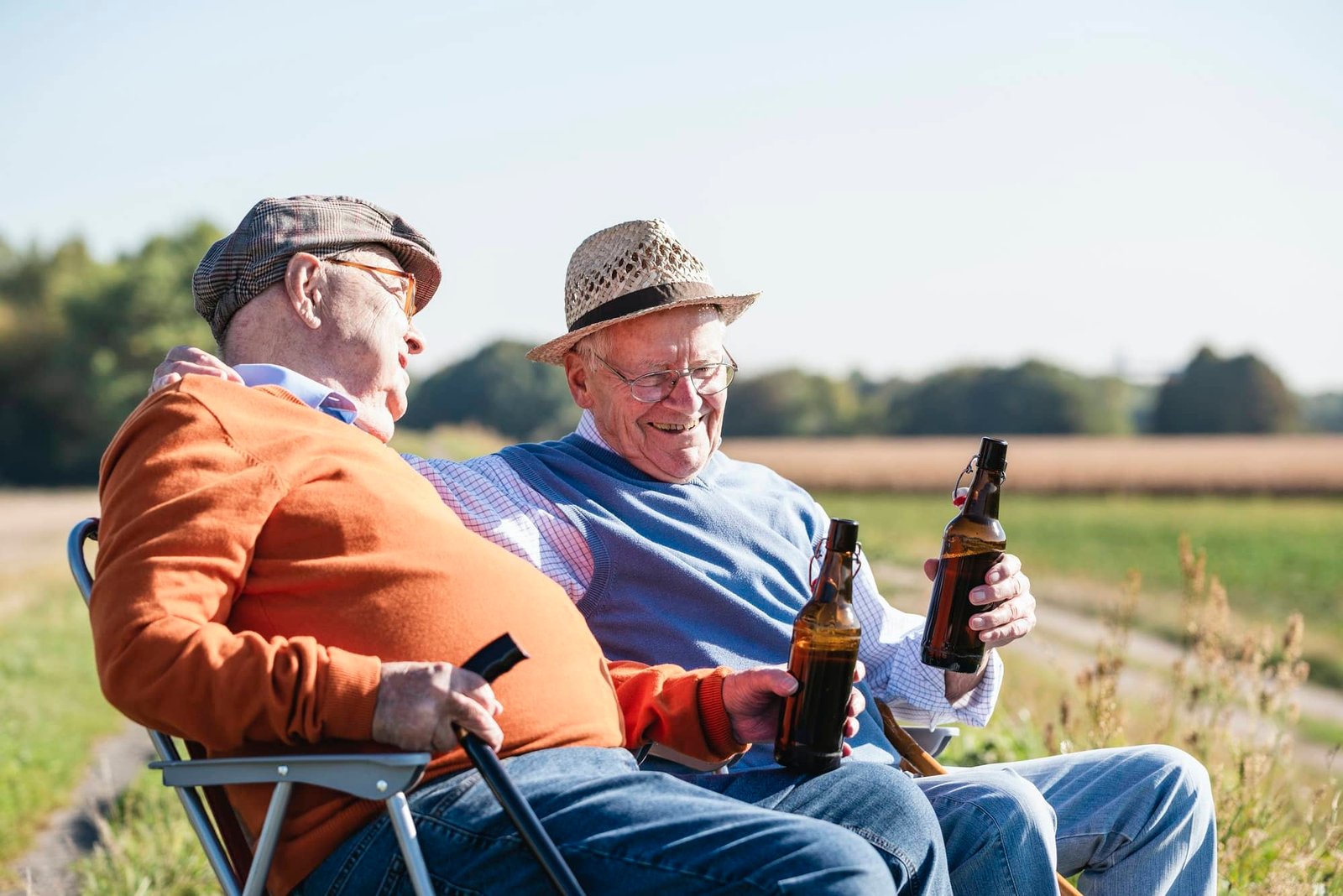 Two former work colleagues sit in the fields, drink beer after a shared lunch, and talk about old times