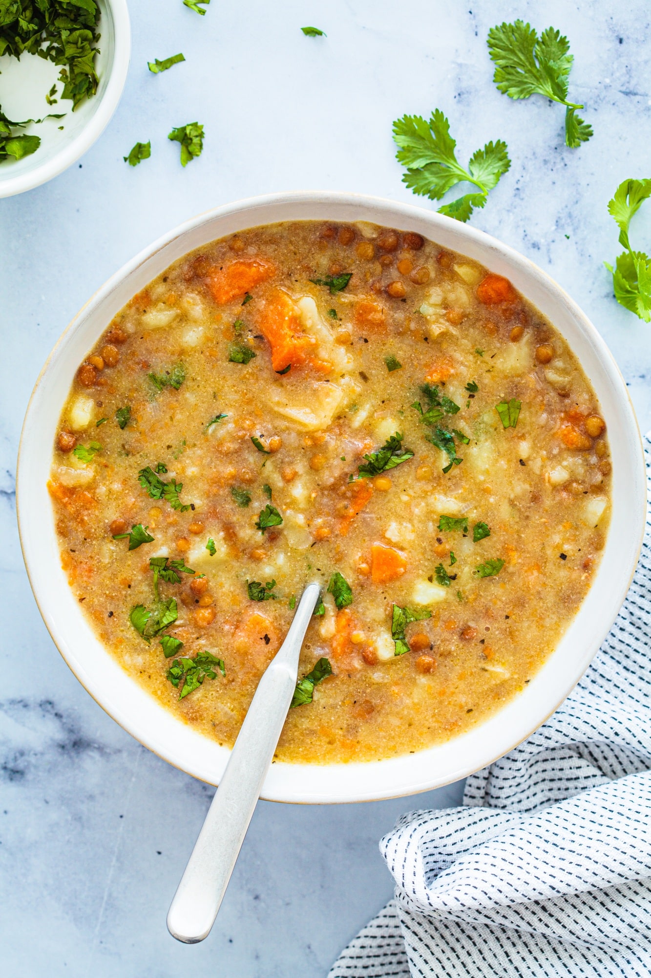 Vegan soup with potatoes, sweet potato and lentils in white bowl. Plant-based recipe.