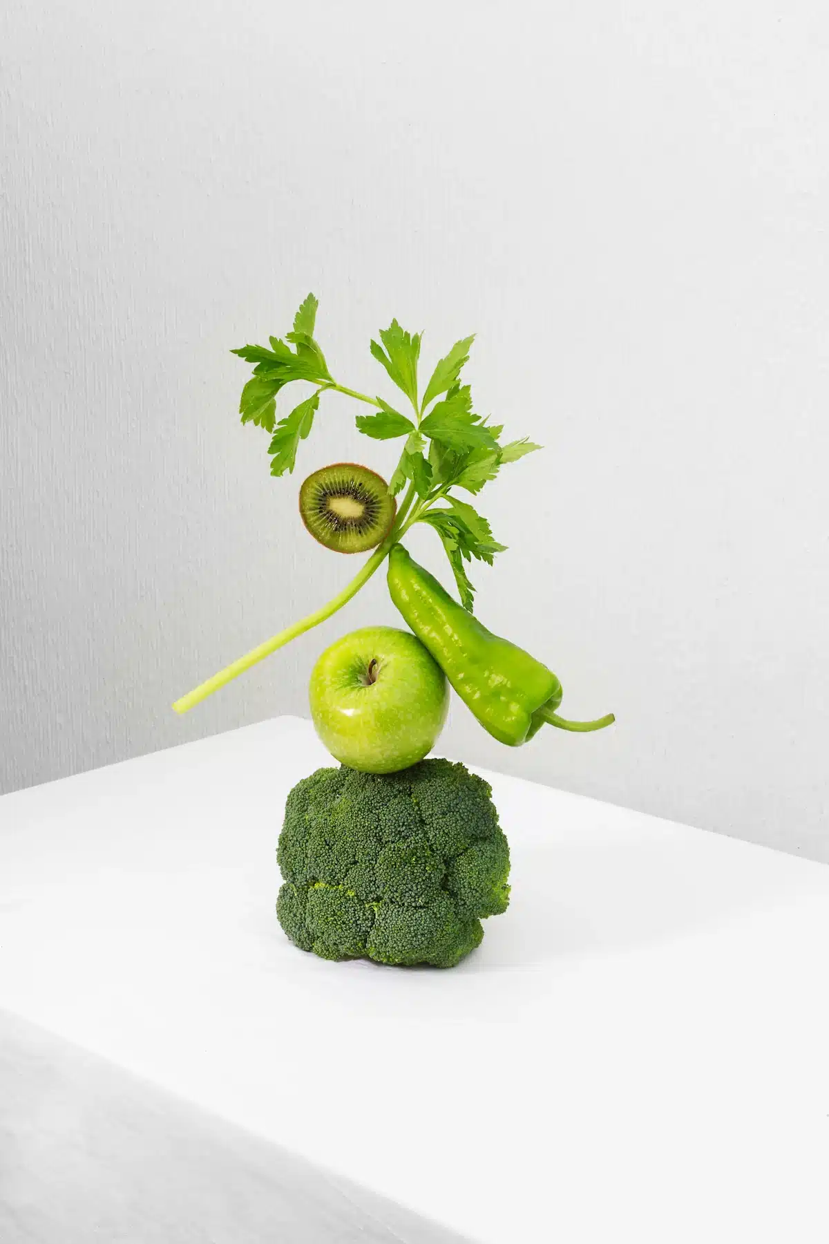 Veggie art comprised of Fresh green vegetables and fruits on white table