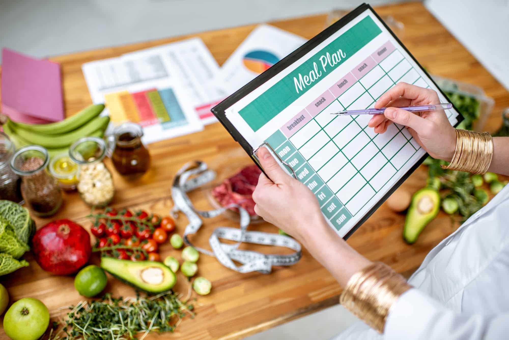 Woman filling in her weekly lunch plans within her overall meal plan on a chart