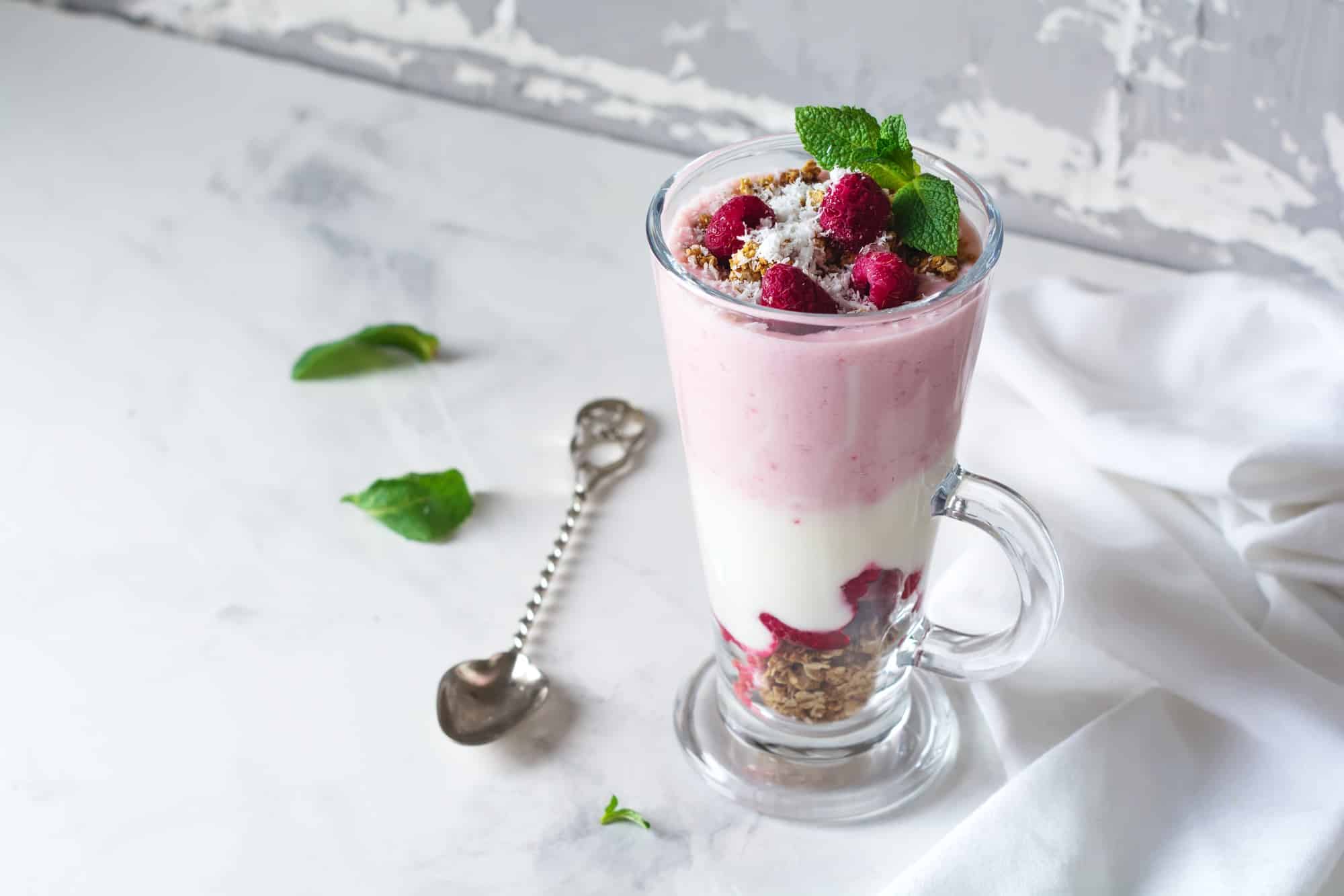 Parfait au yaourt et au granola avec des framboises congelées, des flocons de noix de coco et des graines de chia, dessert en couches ou br