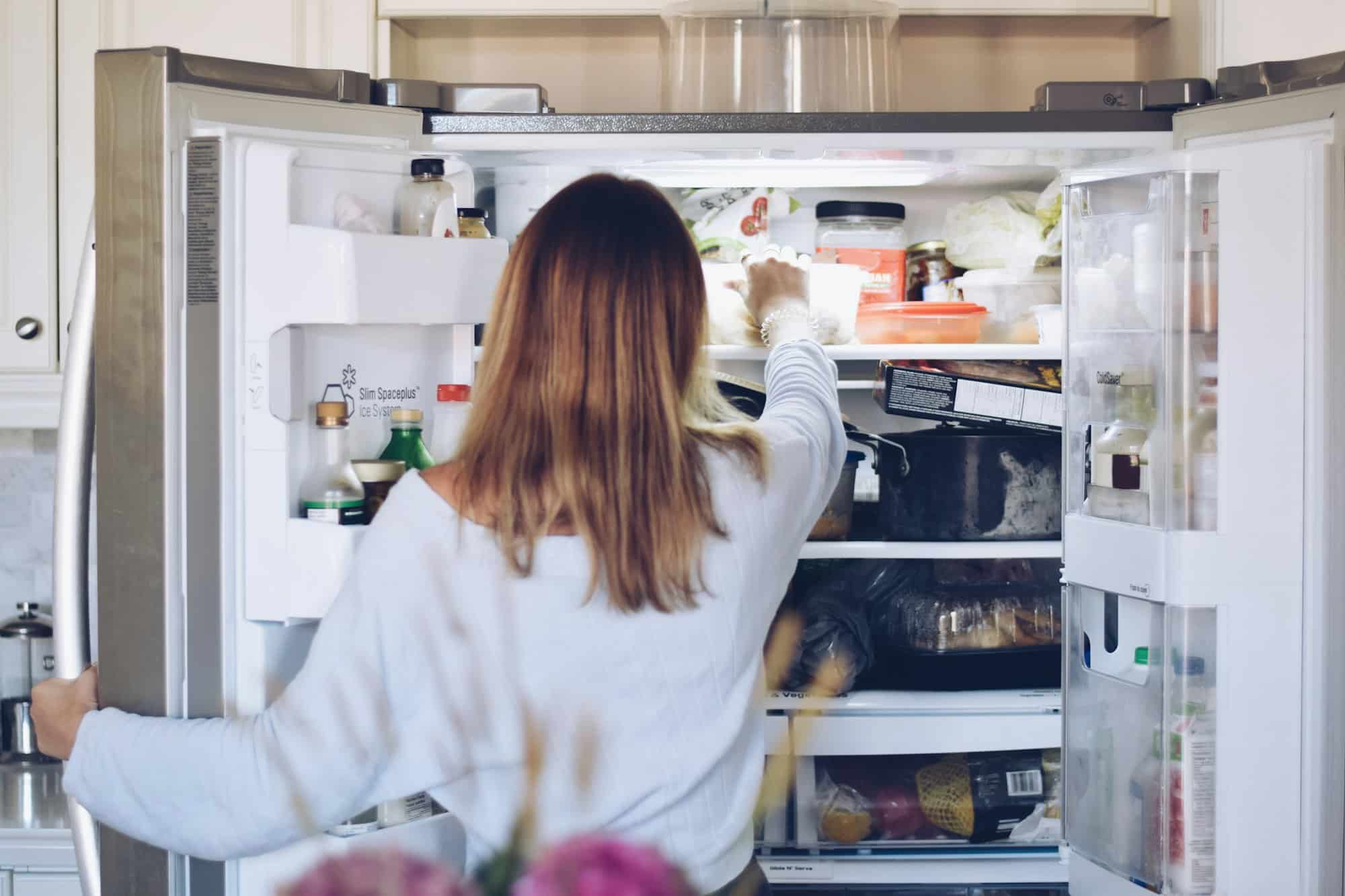A woman takes her food from the other freezer lunches in the office fridge.